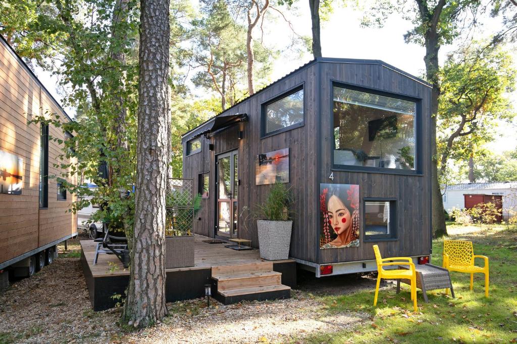 a black tiny house in the woods with two yellow chairs at Tiny House Nr 4 in Schwielowsee