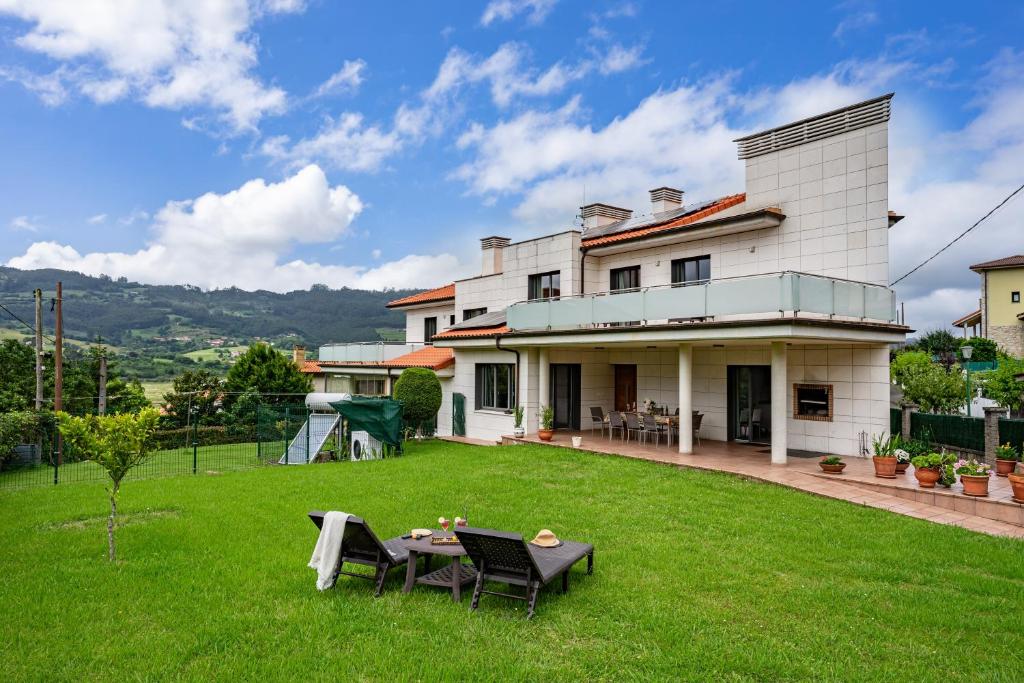 a house with a green yard with a table and chairs at Casa La Manzana in Villaviciosa