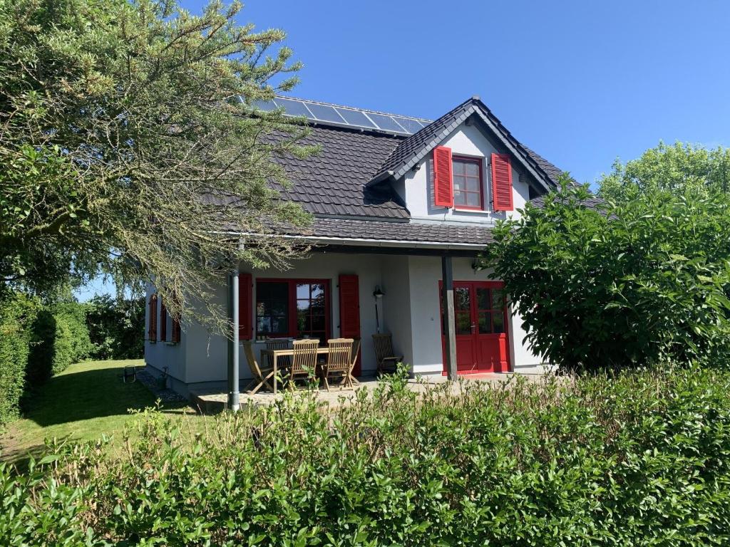 a house with a red door and a yard at Sabines Badehaus mit Innenpool in Steinkoppel