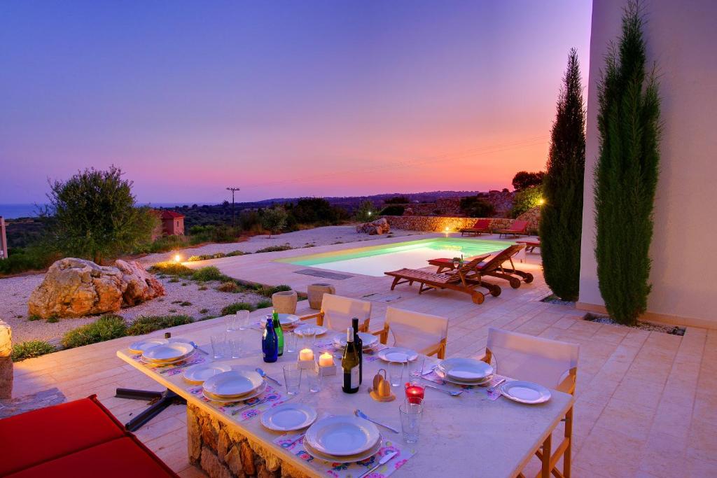a table with plates and wine glasses on a patio at Villa Nautilos Ideales Resort in Kefallonia
