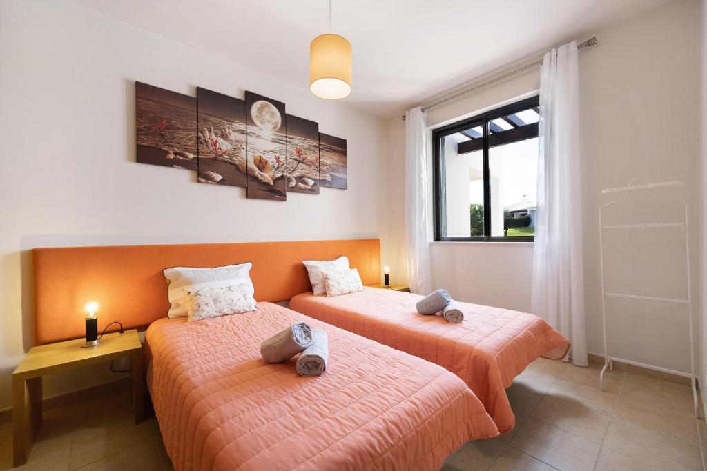 two beds in a room with orange sheets at Duo Village in Alvor