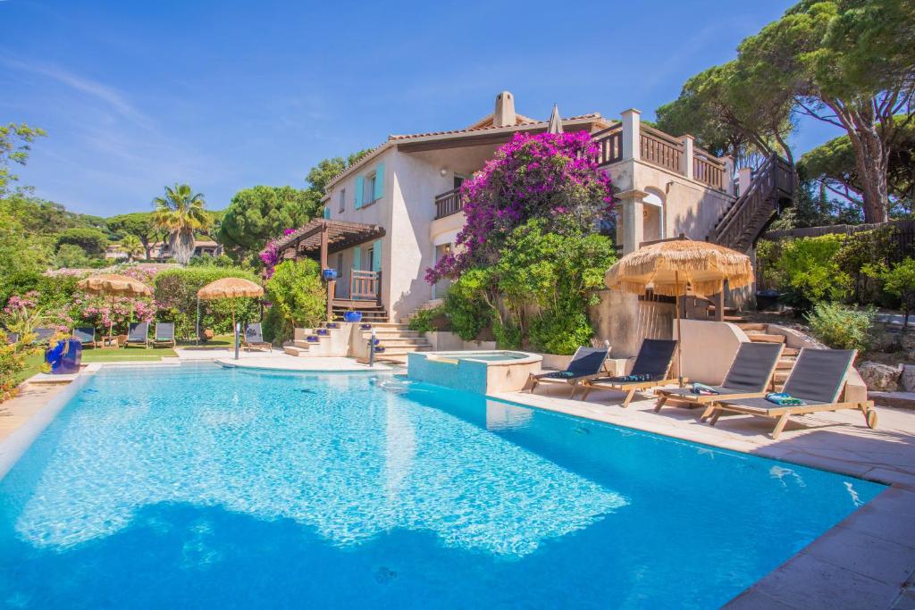 a swimming pool with chairs and a house at Villa à 200m de la plage in Sainte-Maxime