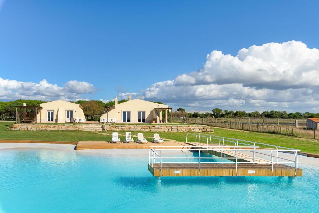 a pool of water with chairs and a house at Paraiso da Serva - Flor do Rosto 1 in Odemira