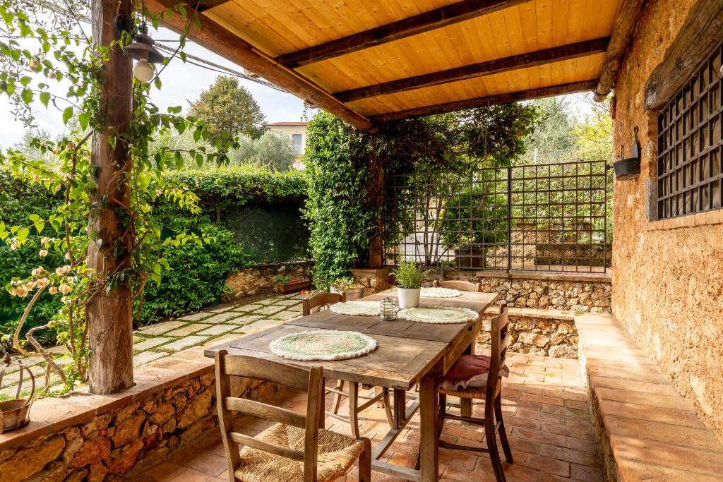 a patio with tables and chairs under a wooden pergola at Greg's House in Santa Lucia