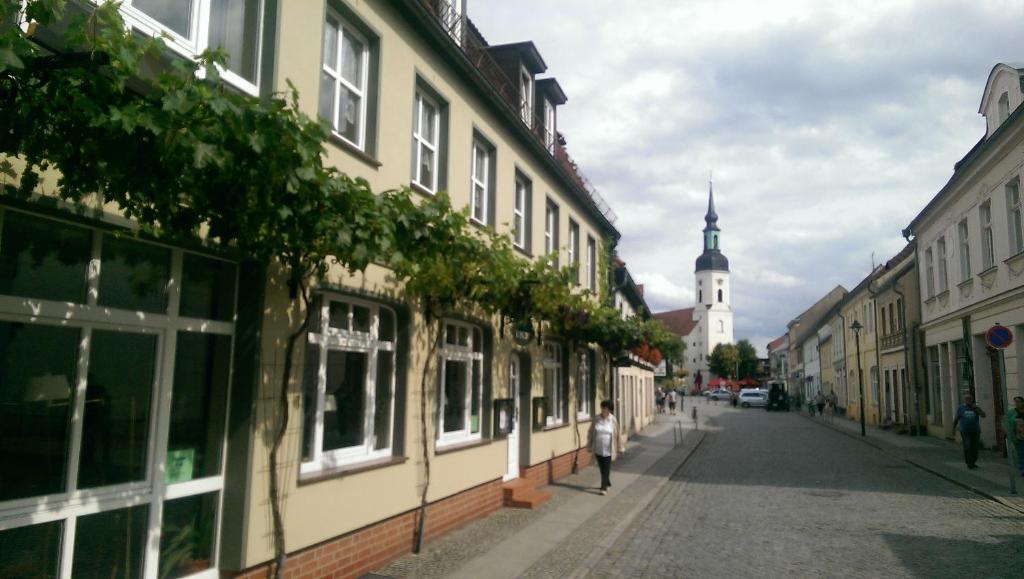 eine Stadtstraße mit Gebäuden und einem Uhrturm in der Unterkunft Lausitzhof in Lübbenau