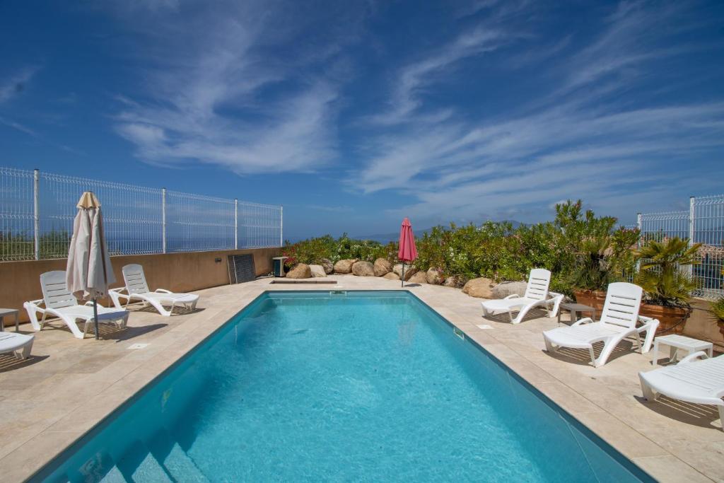 a swimming pool with lounge chairs and a umbrella at Splendide Grand Appart Neuf in Albitreccia