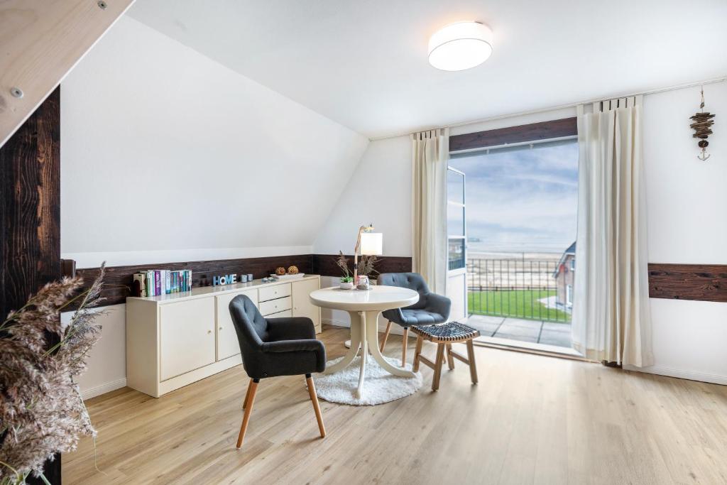 a living room with a table and chairs and a large window at Inselliebe in Pellworm
