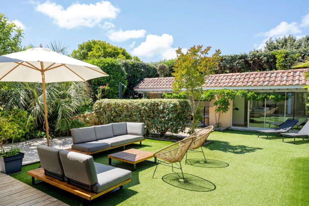 a backyard with a patio furniture and an umbrella at Dune Lodge 1- Capbreton Hossegor - in Capbreton