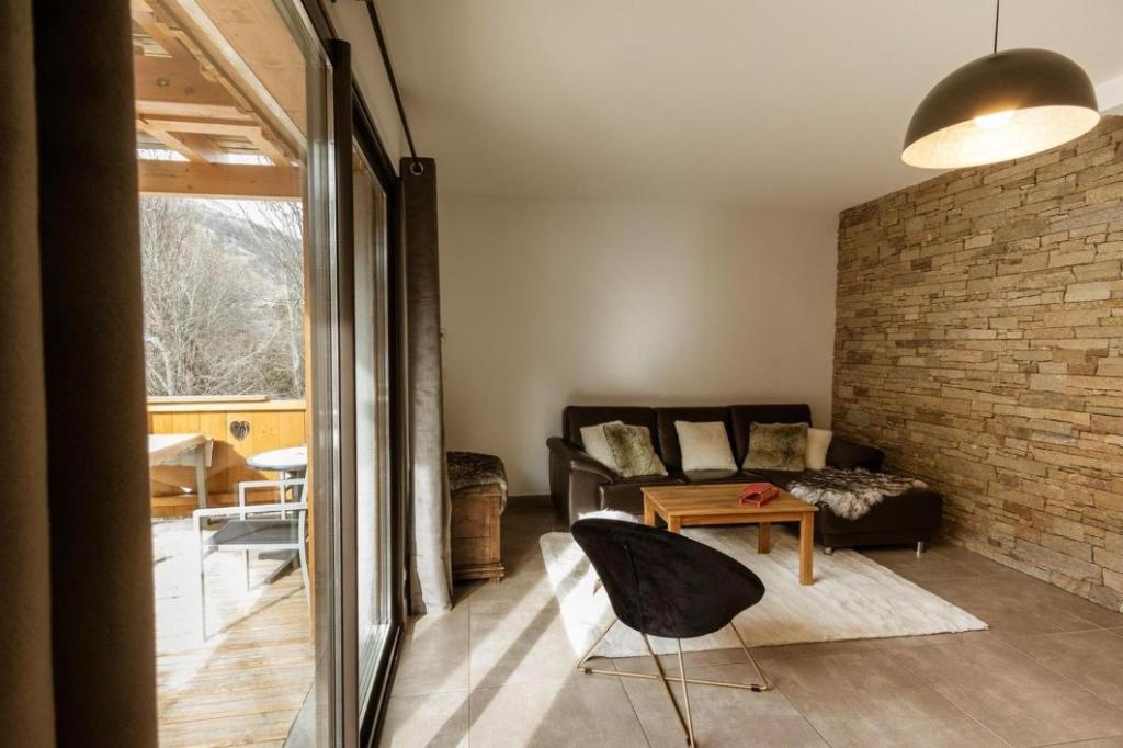 a living room with a couch and a brick wall at Chalet Lova in Valloire