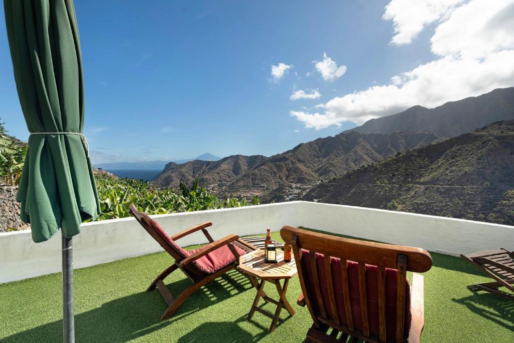 a balcony with two chairs and a table and an umbrella at Casa Tajaraste 1 in Hermigua