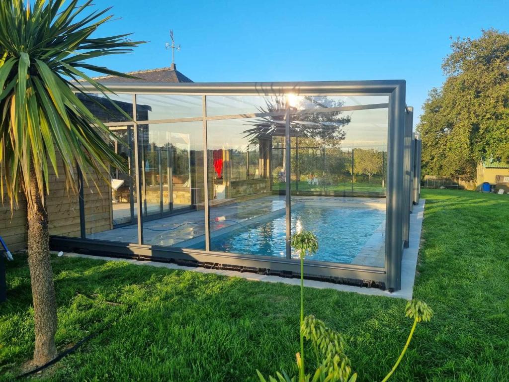 a glass house with a swimming pool in a yard at Gîte Le Jardin d'Eden in Bovel
