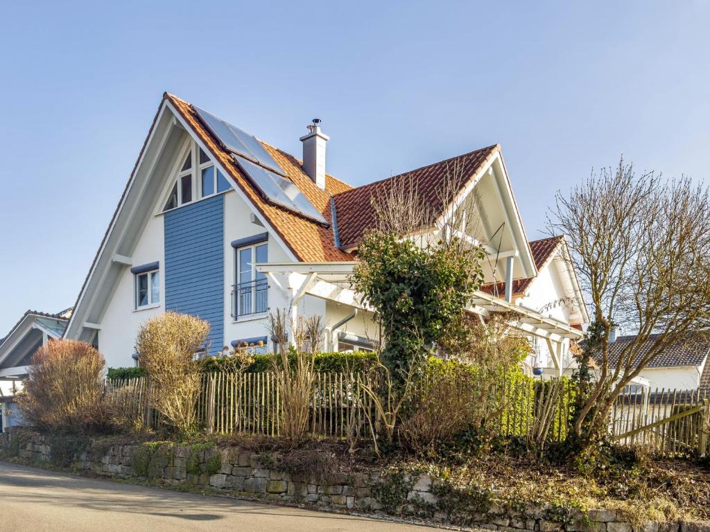 a white house with a brown roof and a fence at Ferienwohnung Meckenbeuren in Meckenbeuren
