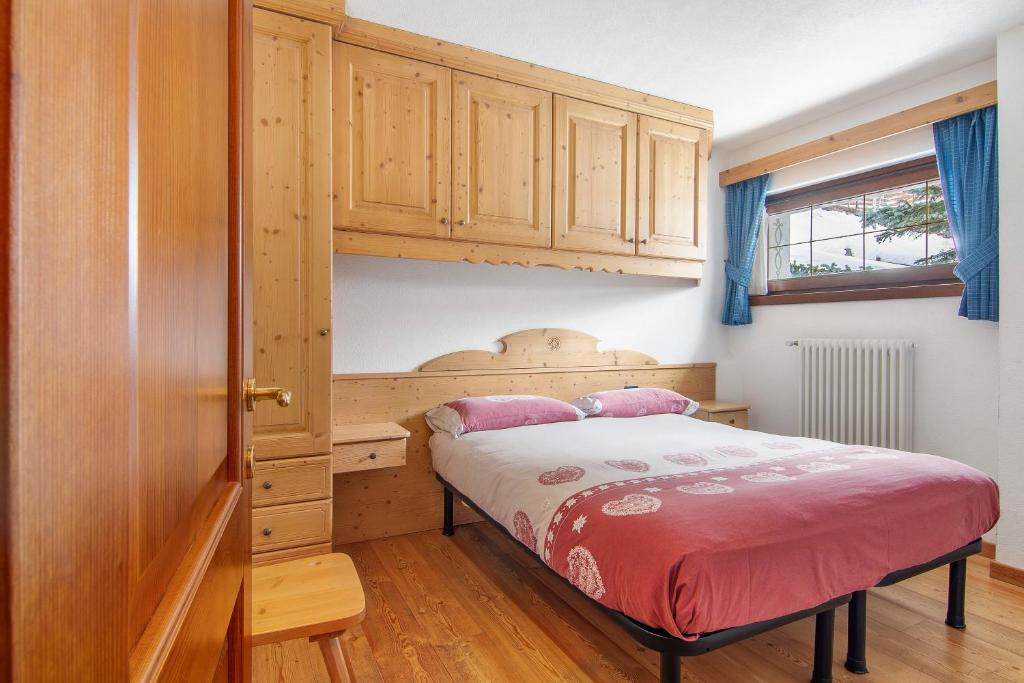 a bedroom with a bed and a wooden cabinet at Residence Larice Bianco App n6 in Campodolcino