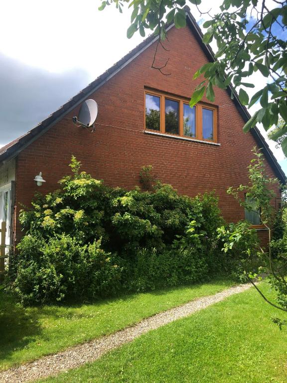 a red brick house with bushes in front of it at Ferienwohnung Lisa in Behrensdorf