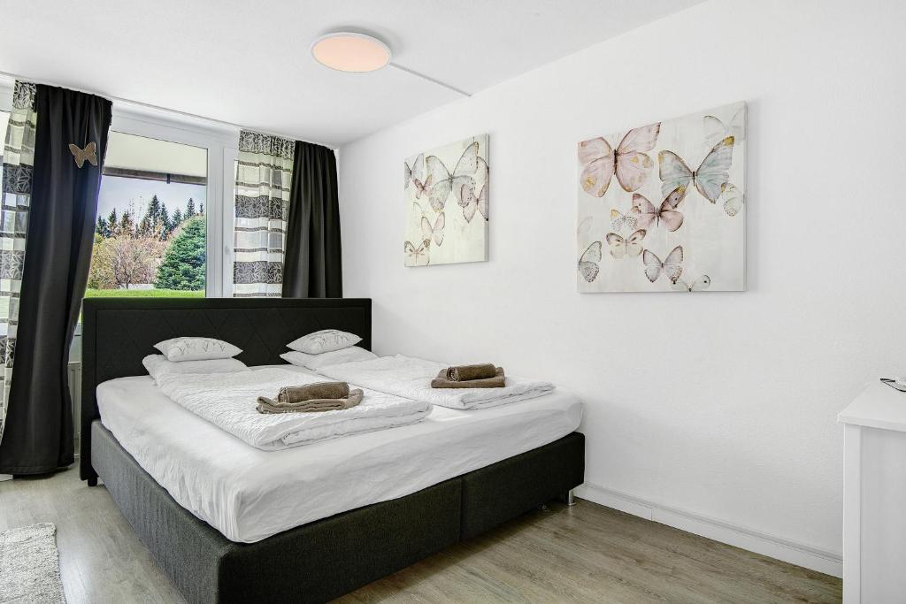 a bedroom with a large bed with white sheets at Ferienappartement Schmetterling in Sankt Englmar