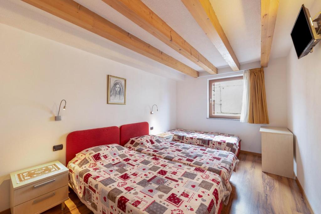 a bedroom with two beds and a red chair at Apartment Latemar Casa Alma in Tesero