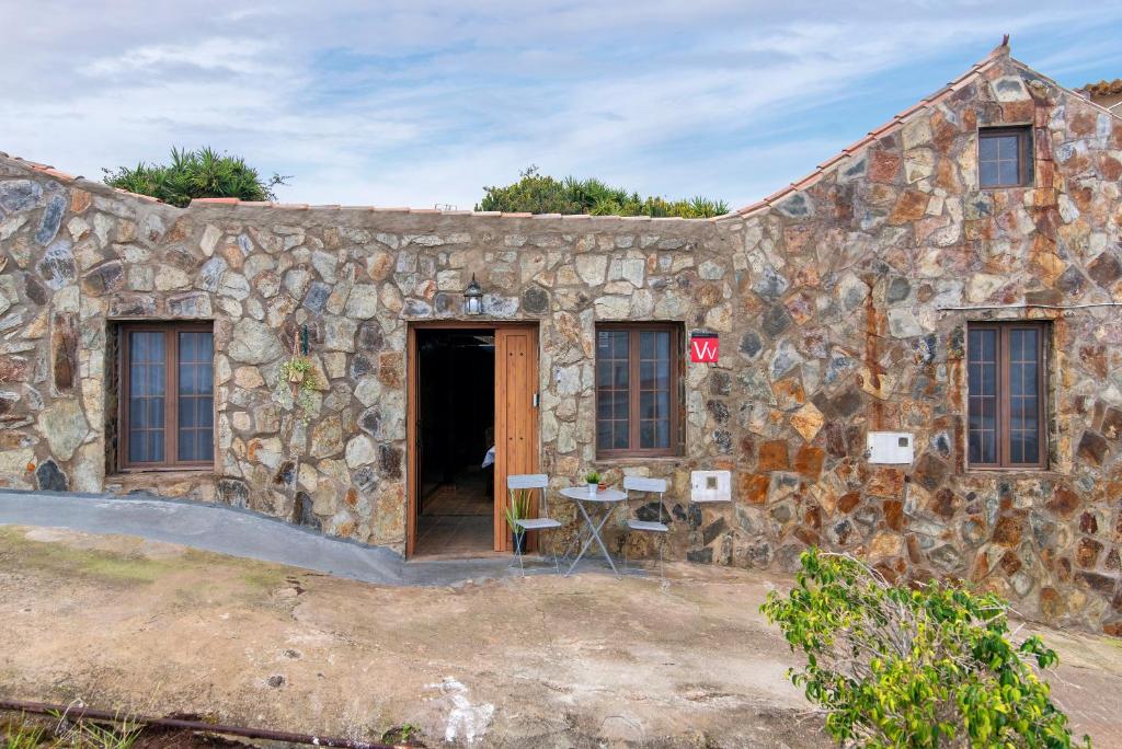 a stone house with a door and a table outside at El patio canario in Firgas