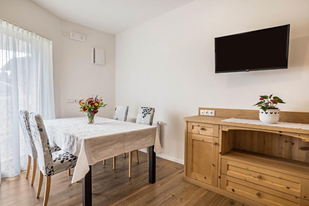 a dining room with a table and a tv on a wall at Ciasa Silvia in San Martino in Badia