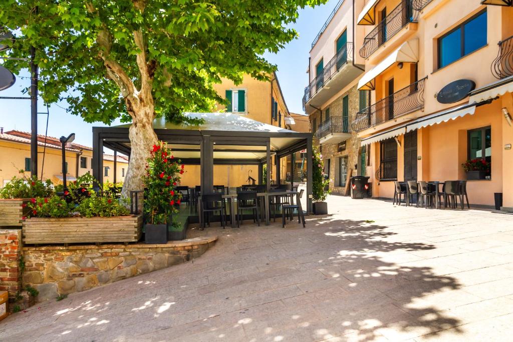 a courtyard with tables and chairs and a tree at Appartamenti Remota in Castiglione della Pescaia