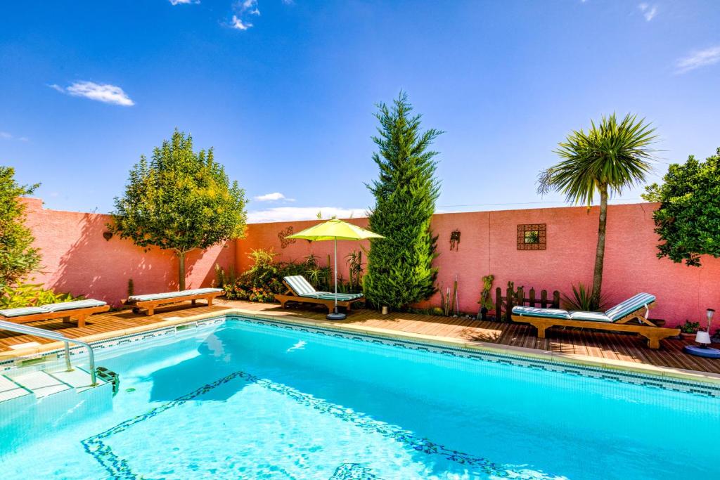a swimming pool with two chairs and a building at Location Fontaine de Sarac in Clermont-lʼHérault