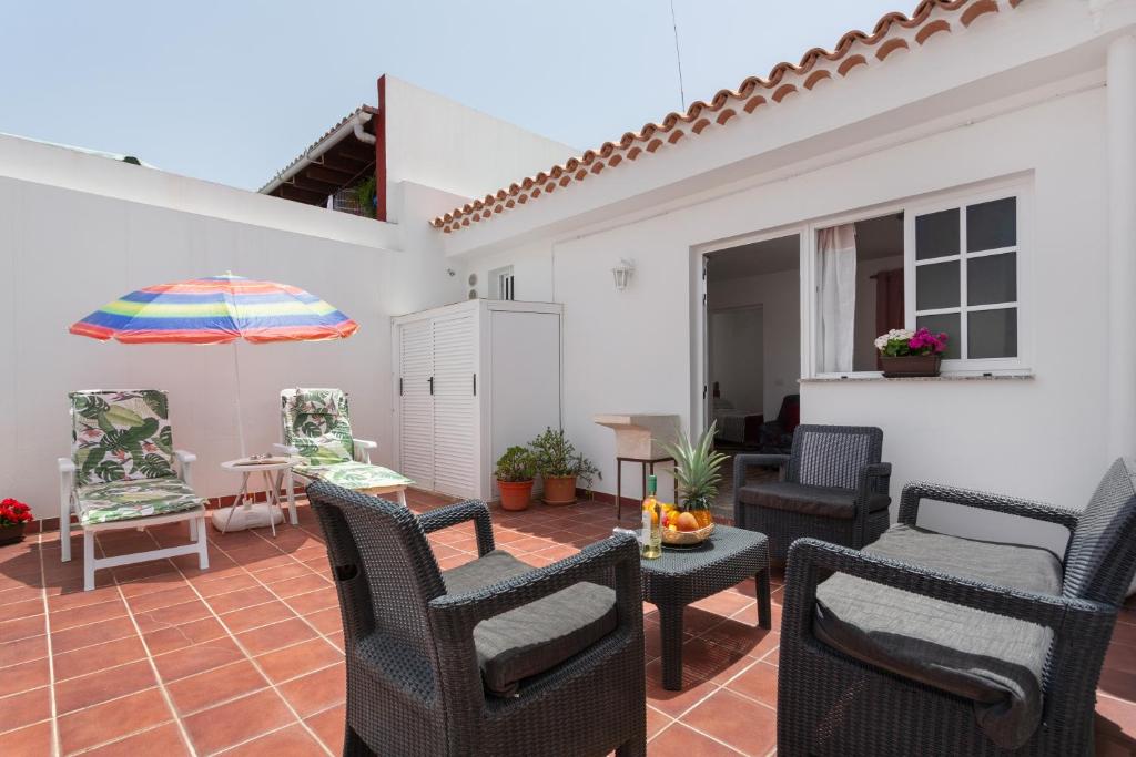 a patio with chairs and a table and an umbrella at Ático La Estrella in Tejina de Isora
