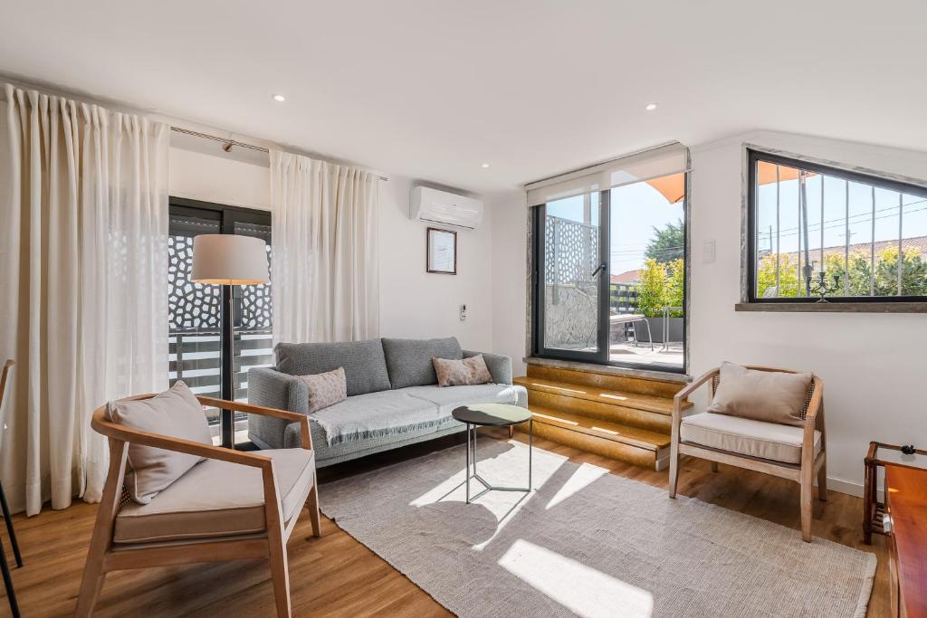 a living room with a couch and chairs and windows at Birre House in Cascais