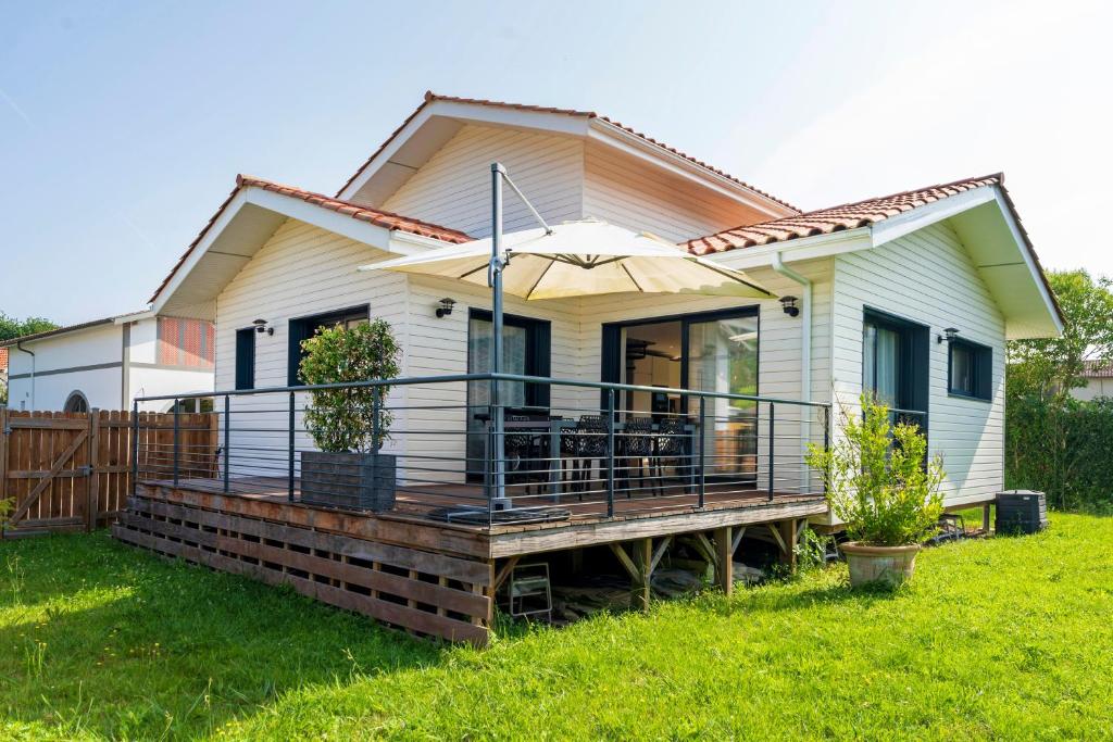 a house with a large deck with an umbrella at Escapade Tout Confort - Seignosse in Seignosse