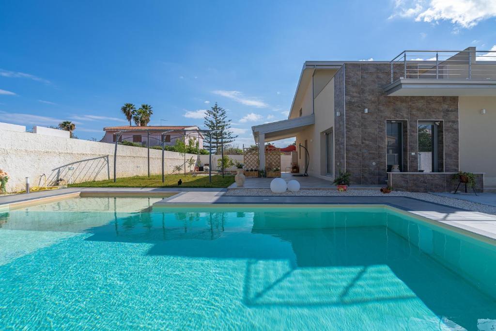 a swimming pool in front of a house at Villa Sele Fontanebianche - Sud in Fontane Bianche