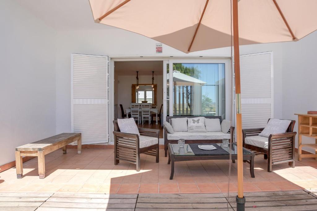 a patio with a table and chairs and an umbrella at Michalete Fernando - Sólo Familias in Conil de la Frontera