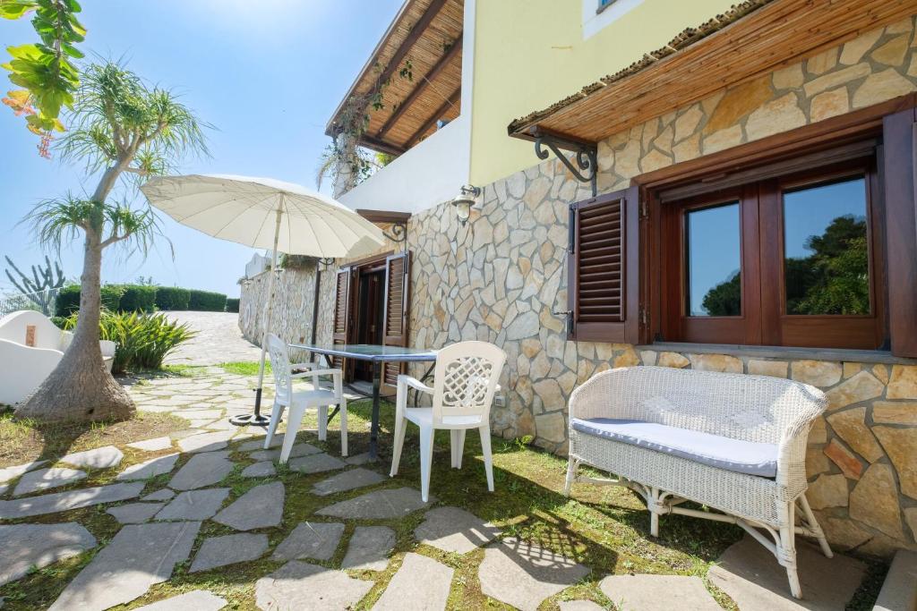 a patio with a table and chairs and an umbrella at Casa della Poiana in Lipari