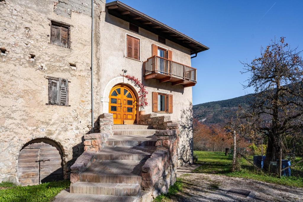 an old building with a wooden door and stairs at Appartamenti l'Edera in Cavedago