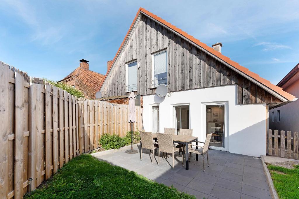 a house with a wooden fence and a table and chairs at Küstenliebe-Fehmarn in Fehmarn