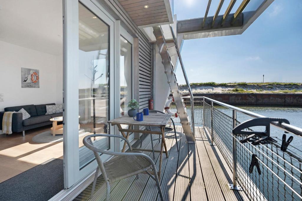 a balcony of a house with a table and chairs at Hausboot Sutje in Großenbrode