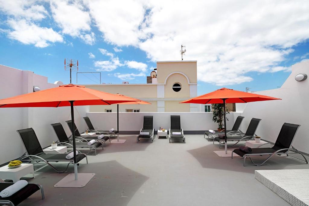 a patio with chairs and umbrellas on a building at Apartamento La Estrella 4 in Arrecife