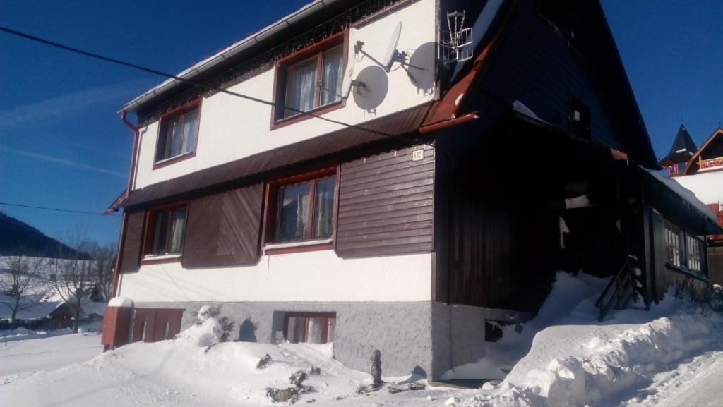 Un edificio cubierto de nieve con nieve a su alrededor. en Privat u Babky, en Ždiar