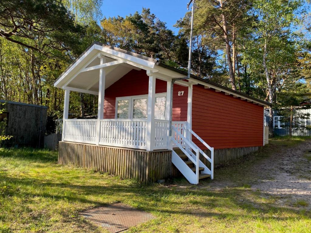 a red house with a porch and a white deck at Lillis Ferienhaus Nr 27 in Göhren