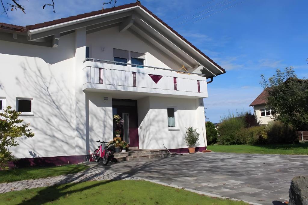 a white house with a balcony on the side at Ferienwohnung am Wiesenweg in Mauerstetten