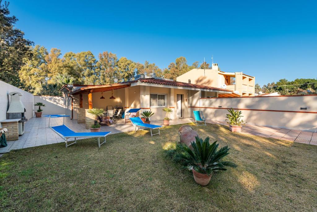 a backyard with blue chairs and a house at Ibiscus Rosa 1 in Marongiu