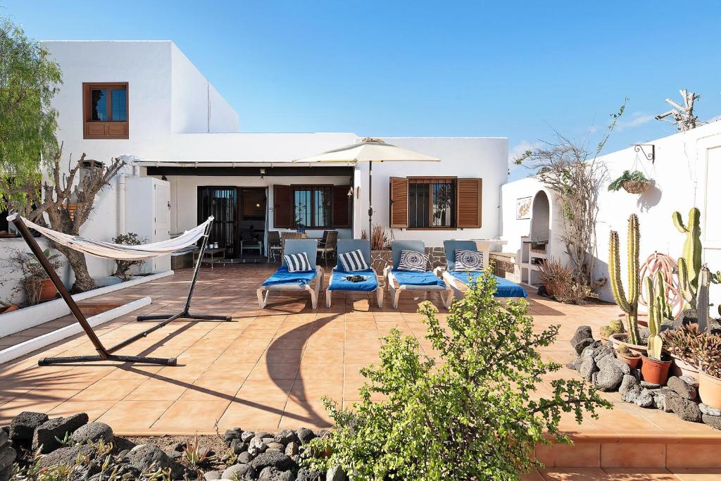 a patio with chairs and a hammock in front of a house at Puerto Chico A in Playa Blanca