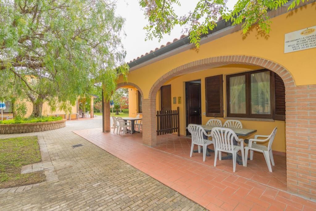 a patio with tables and chairs on a yellow house at Il Girasole - Malva in Venturina Terme