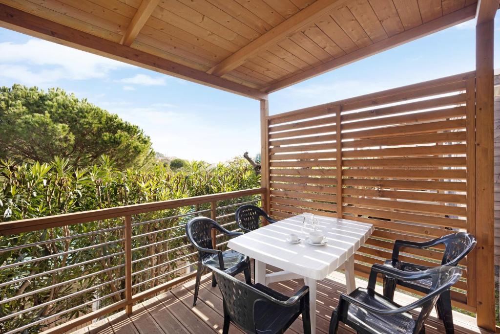 a white table and chairs on a wooden deck at Mobile Home Alloro 165 in Pietra Ligure