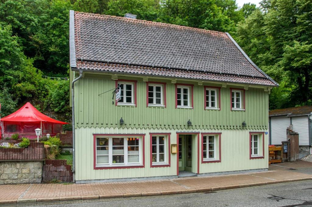 a green house with white windows and a red roof at Altes Höhlenführerhaus in Rübeland