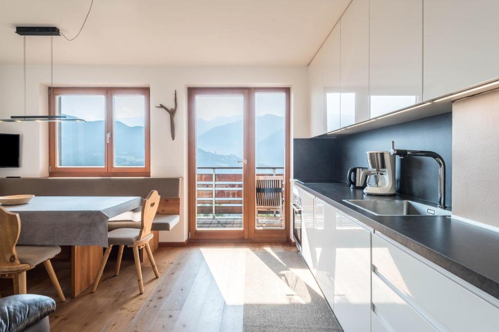 a kitchen with white cabinets and a table with chairs at Thalerhof App Melisse in Feldthurns