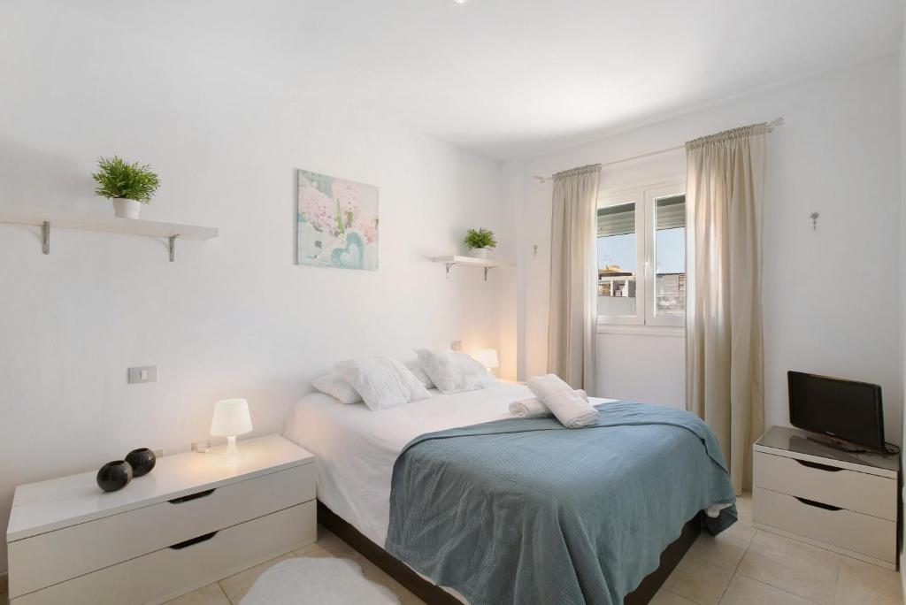 a white bedroom with a bed and a television at Ático Garajonay in Cabo Blanco