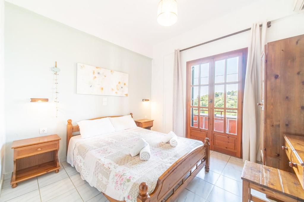 a white bedroom with a bed and a window at Arianna apartment 10 in Paleokastritsa