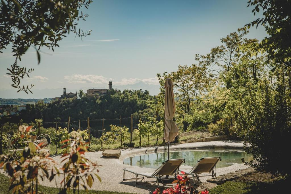 a swimming pool with two chairs and an umbrella at Cascina Voglietti - Private Pool in Murisengo