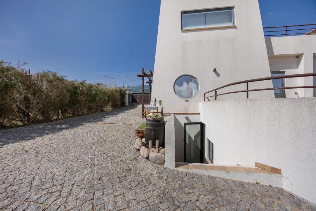 a white house with a brick road next to a building at Apartment Amado - Carrapateira in Carrapateira