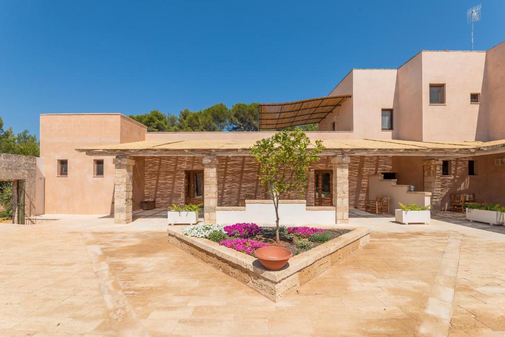 a building with a courtyard with flowers in front of it at Masseria Scafazzi - Salento in Presicce