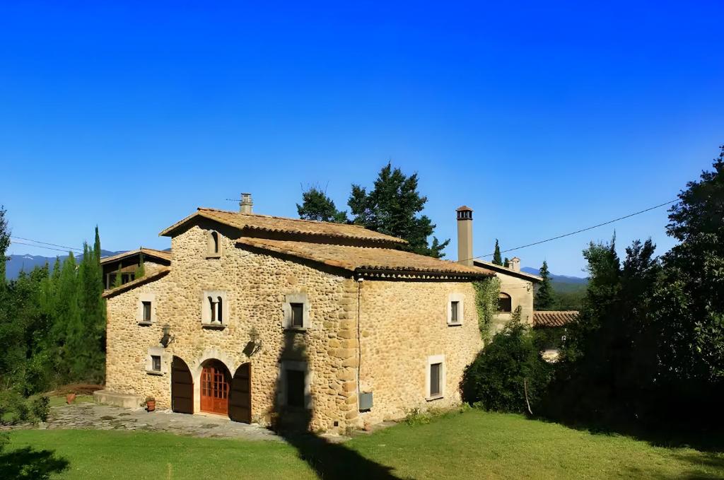 an old stone house on a grassy field at El Revolt de Martís in Esponellá