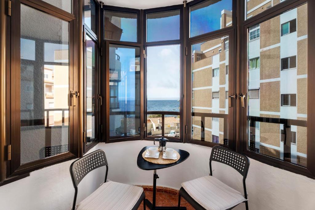 a room with large windows with a table and chairs at Tamaragua in Candelaria